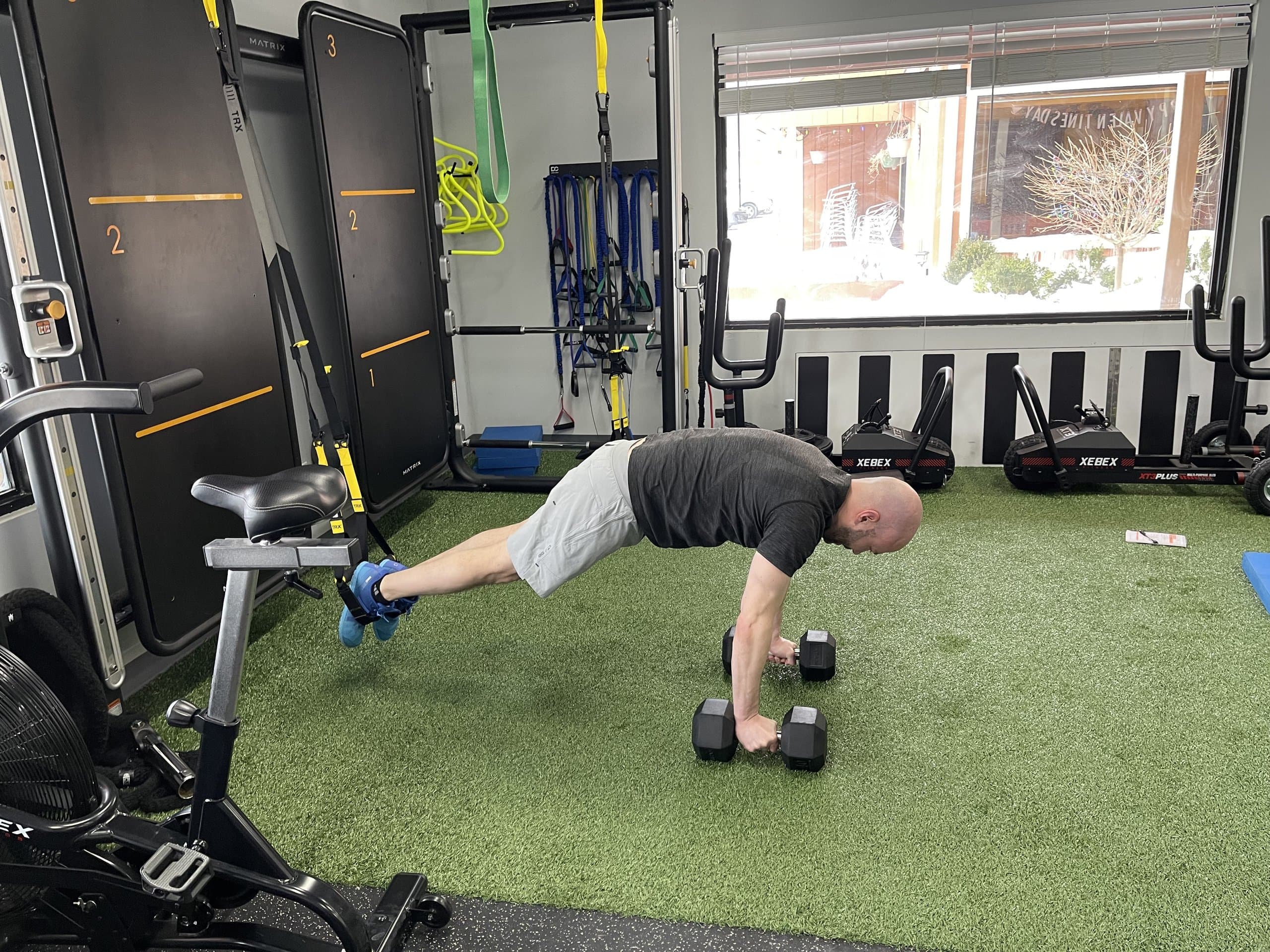 A member holding a dumbbell plank at 838 Strength and Fitness in Monroe, CT