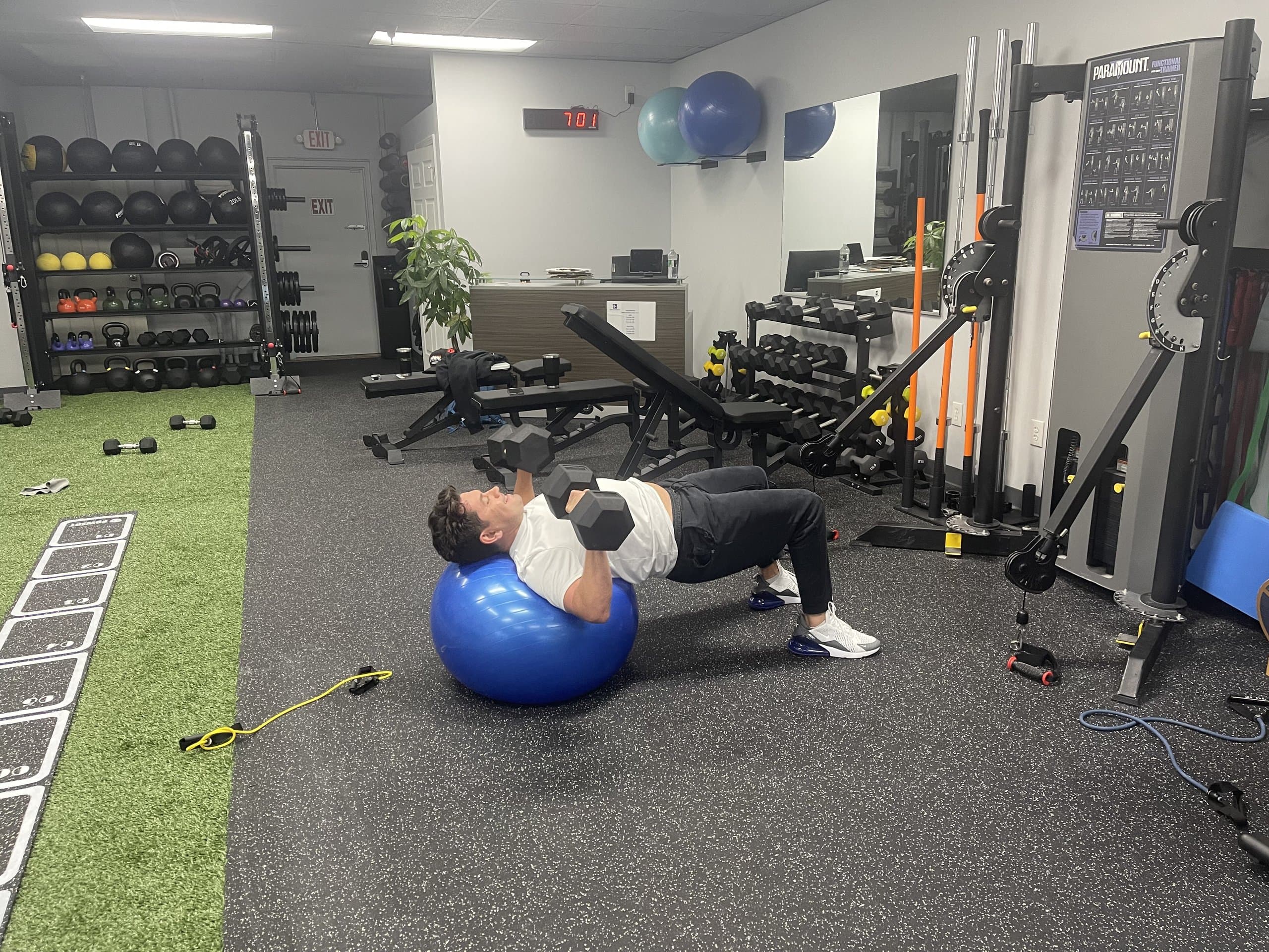 A member performing a dumbbell chest press on a stability ball at 838 Strength and Fitness in Monroe, CT