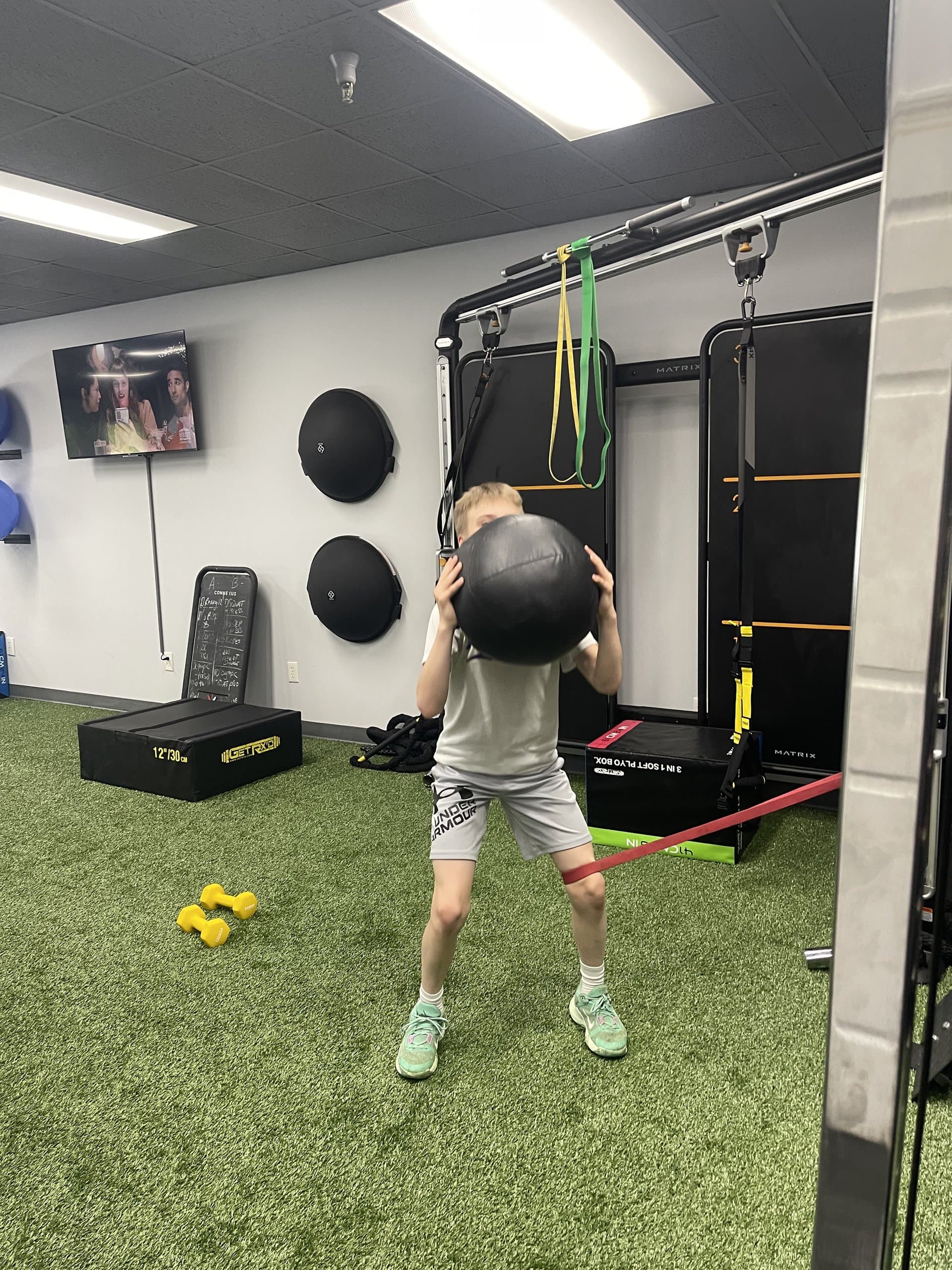 A young athlete pressing a medicine ball overhead at 838 Strength and Fitness in Monroe, CT