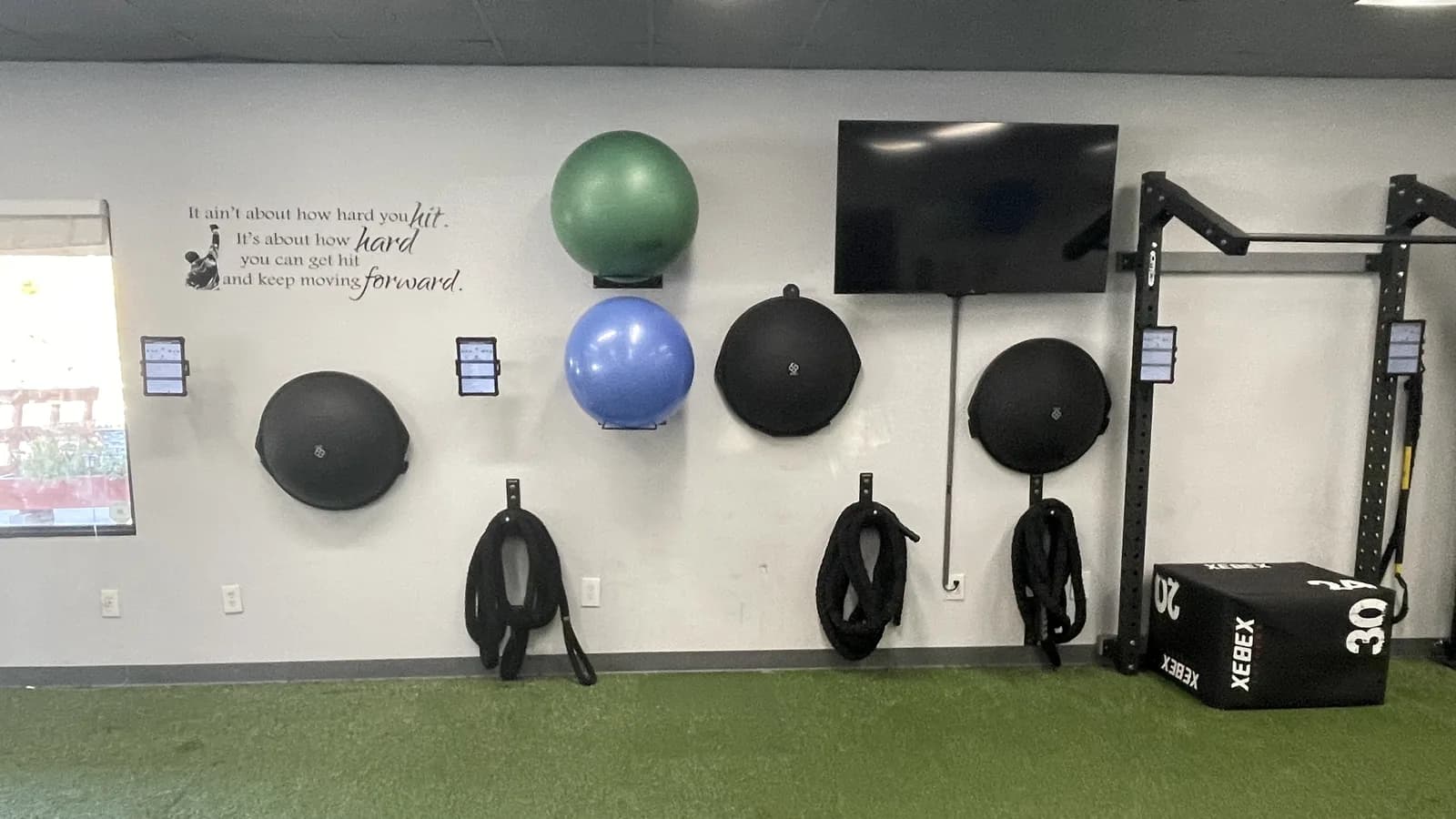 Members' workout tablets mounted on the wall of the training floor at 838 Strength and Fitness in Monroe, CT